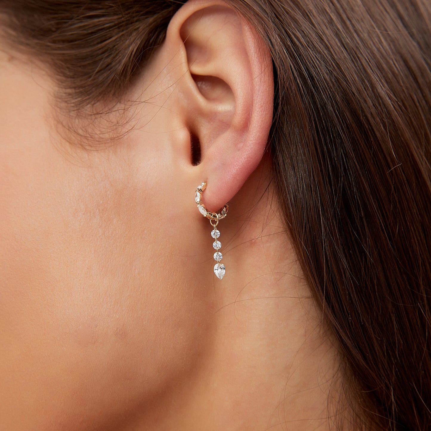 Close-up of an ear wearing a delicate earring with small beads.
