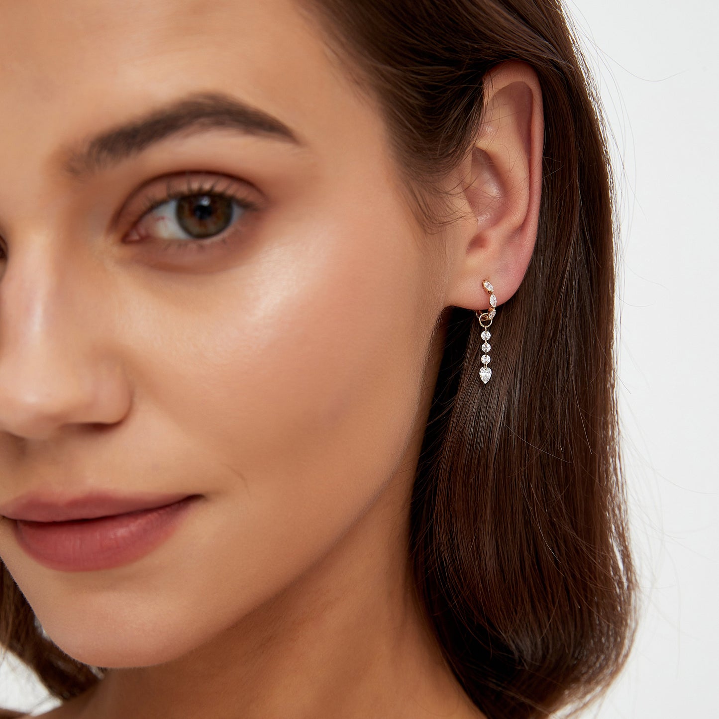 Close-up of a woman wearing a dangling earring with a white background