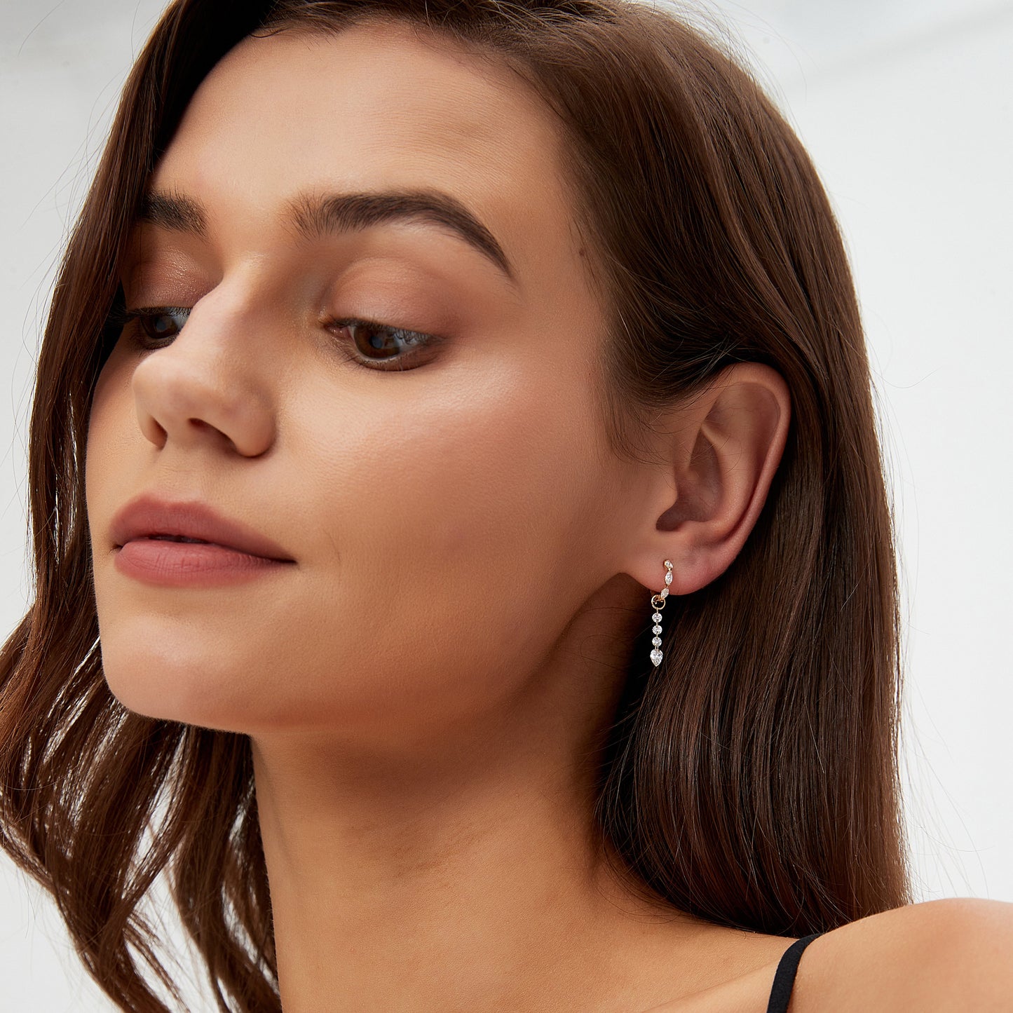 Close-up of a woman wearing a black strappy top with a plain background