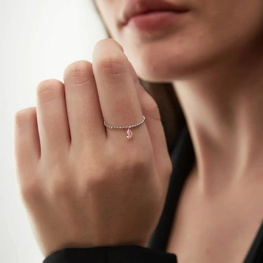 Macro view of the pink pear-cut lab-grown diamond on the LTM & CO. chain ring. Highlights the innovative laser-drilled hole and 18K solid gold link passing through the stone. No prongs or bezel, maximizing brilliance and showcasing the brand's signature floating setting and precision craft.