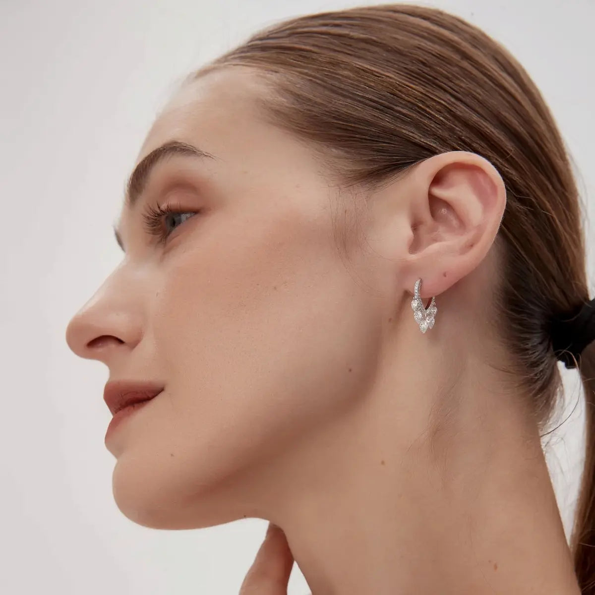 A technical side profile view of the Heart Dangle Full Pavé Hoop by LTM Jewels. This image highlights the structural integrity of the 18K solid gold hoop hinge and the secure connection of the detachable heart dangle. The profile view showcases the multidimensional nature of the pavé setting and the depth of the heart-shaped frame. The consistent high-polish finish of the AU750 gold is clearly visible, demonstrating the premium quality and refined silhouette of this versatile 2-in-1 design.