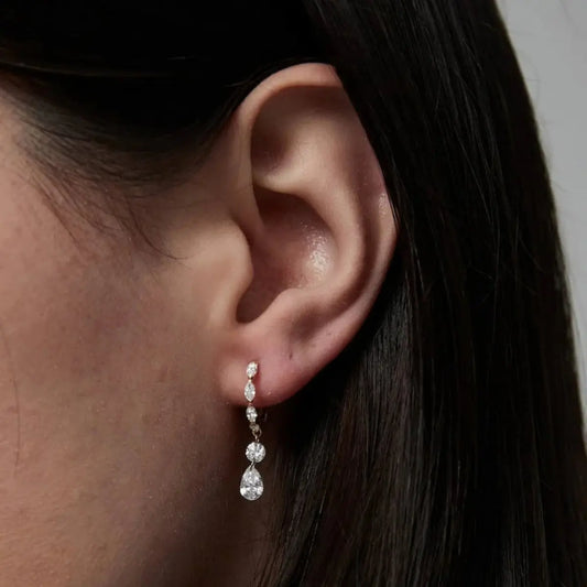 Macro view of the LTM & CO.™ marquise diamond dangle hoop. Highlights the innovative laser-drilling technique where the 18K solid gold loop passes through the diamond. No prongs or bezel, exposing the diamond's sharp facets and brilliance. Showcases the brand's commitment to precision architectural craftsmanship.