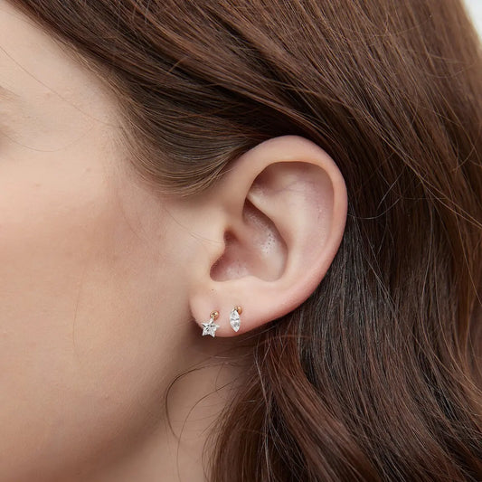 This macro close-up provides an intimate view of the exceptional craftsmanship behind the Star-Cut Diamond Stud by LTM & CO. The high-resolution focus reveals the intricate facets of the star-shaped lab-grown diamond, showcasing a perfect symmetry that creates a brilliant internal play of light. A key highlight of this shot is the precision-engineered laser-drilled hole at the top of the diamond, where a delicate yet durable 18K solid gold loop connects the stone directly to the stud post. By removing tradi