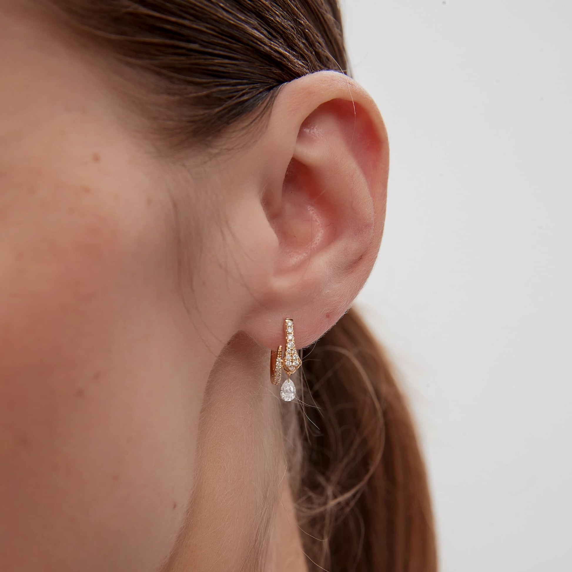 Detailed side profile of the Serpentine Snake White Diamond Pear Drop Hoop, showcasing the 10mm inner diameter and the secure, seamless click-to-close hinge mechanism crafted in 18K solid gold. The image highlights the sturdy gold construction and the hypoallergenic properties of the Au750 metal, ensuring a flush and comfortable permanent fit for active lifestyles. The profile view illustrates how the pear-shaped diamond dangle hangs gracefully, maintaining the hoop's balanced and sculptural silhouette.