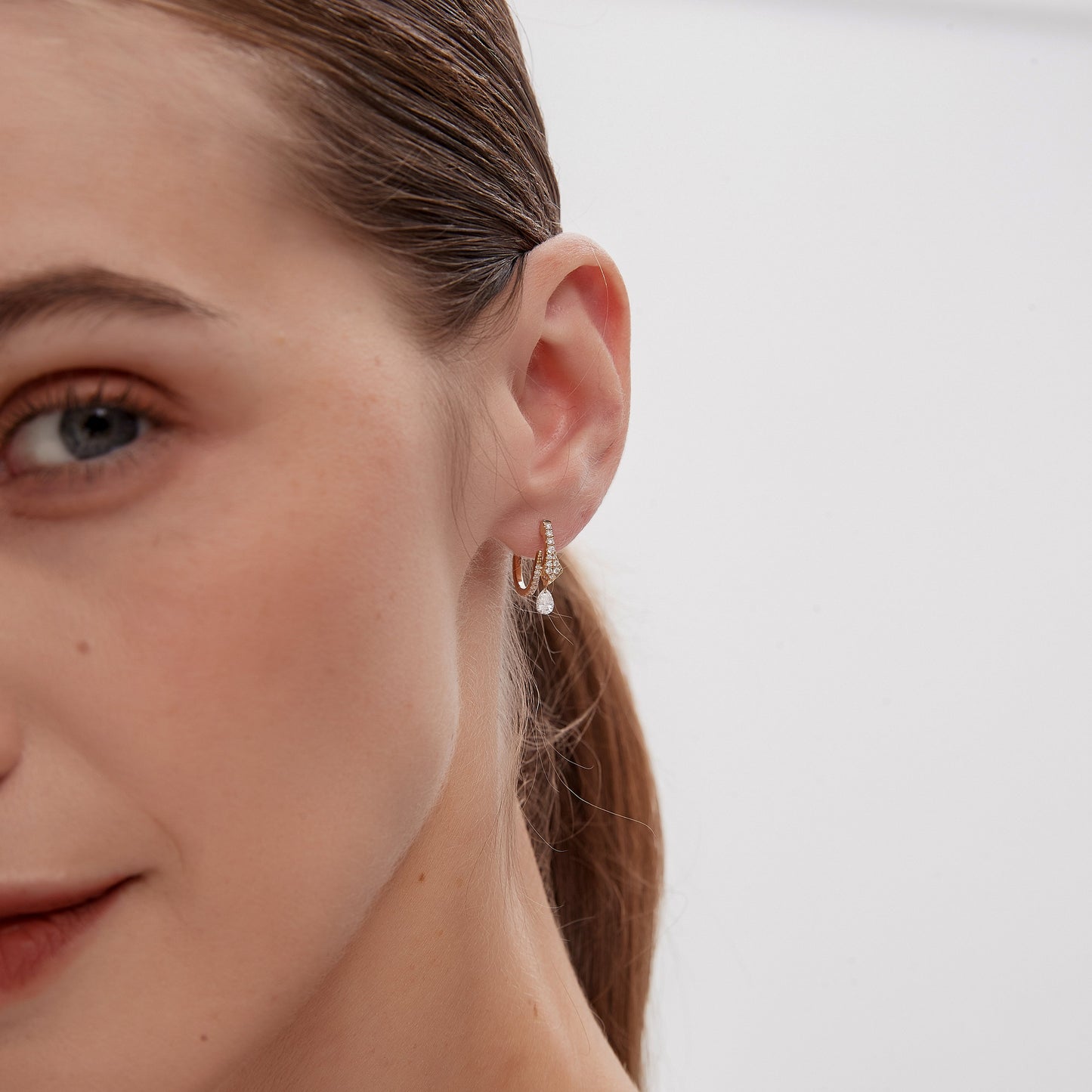 Close-up of a woman wearing gold hoop earrings with a blurred background