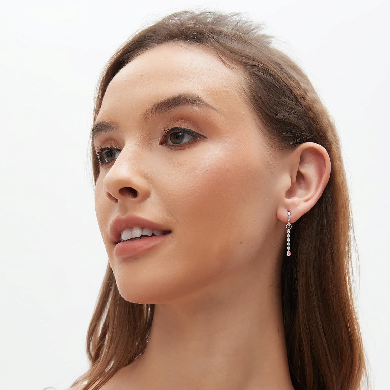 A fashion editorial shot featuring a model wearing the Blush Pink Pear Diamond Drop Charm as part of an avant-garde ear curation. The image captures the modern elegance and poetic motion of the piece, showcasing its role as a contemporary heirloom. The cinematic radiance of the pink pear-shaped dangle is highlighted against a minimal aesthetic, reflecting the sustainable luxury and architectural light philosophy of LTM Jewels.