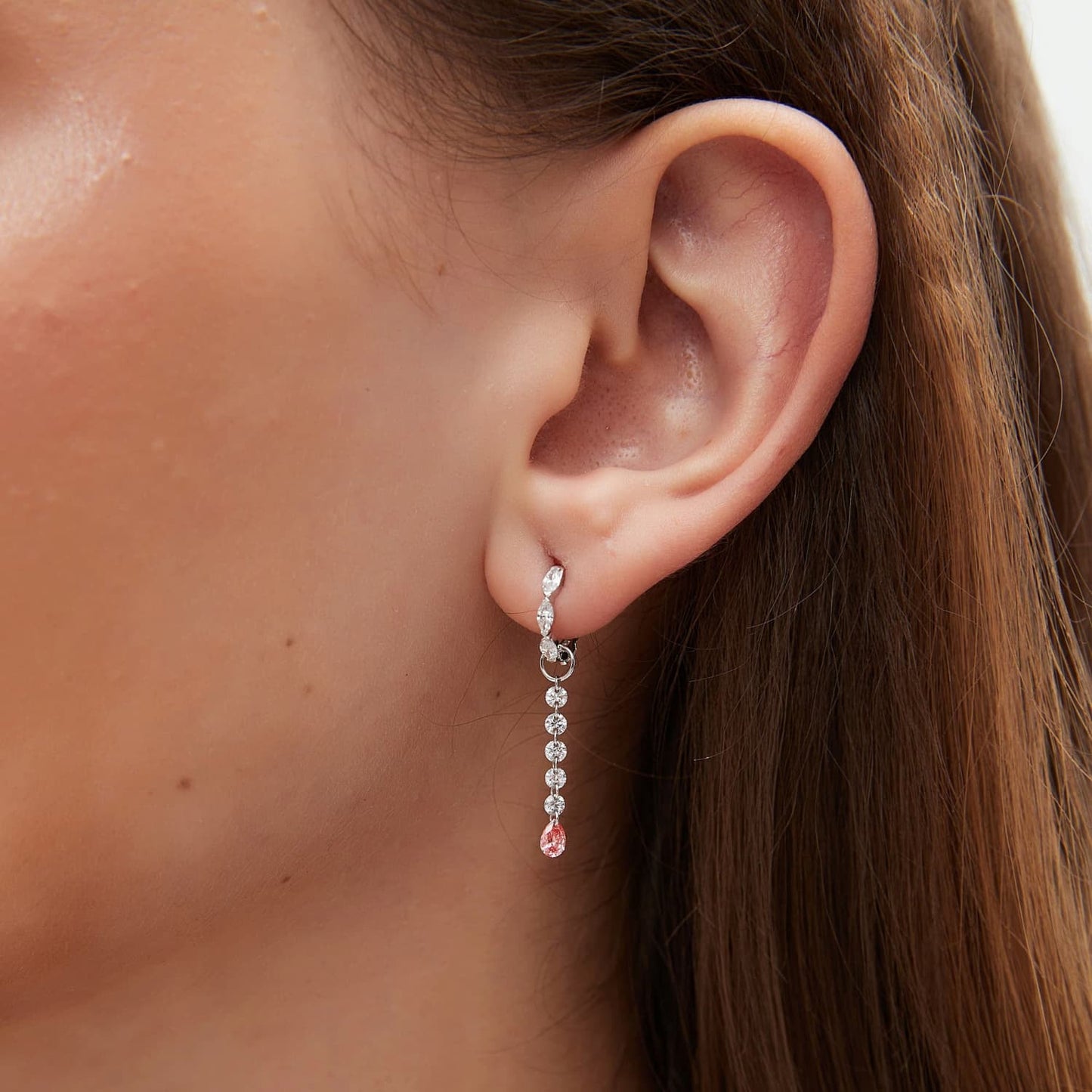 A detailed macro close-up focusing on the shimmering white diamond arc and the rare blush-colored pear-shaped diamond. The photograph reveals the exceptional VVS-VS clarity of the 0.20ctw stones and the precision of the handcrafted 18K gold link. It highlights the delicate contrast between the crystalline purity of the white accents and the captivating pink hue, illustrating the high-end artistry of the LTM Jewels Radiant Drift collection.