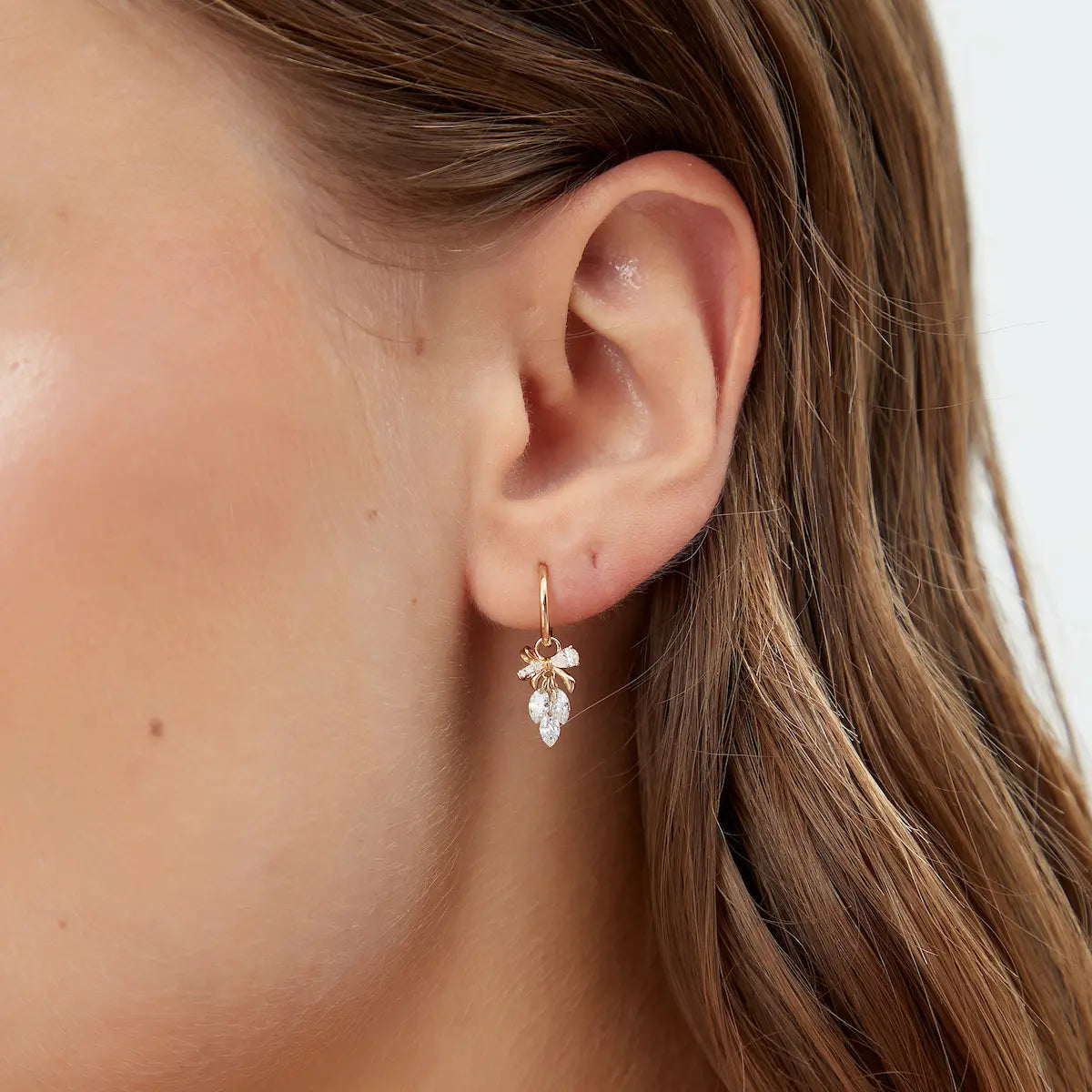 Close-up of 18K Solid Gold Bow & Plume Floating Lab Diamond Charm, highlighting shiny gold finish and floating diamond detail.