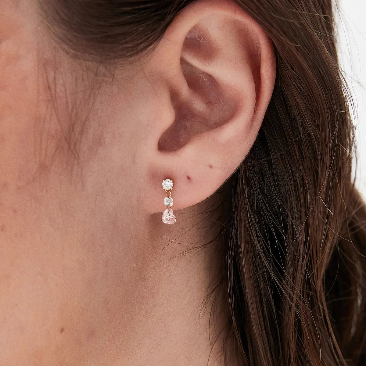 Macro close-up of the Pink Heart Floating Diamond Stud handcrafted in solid 18K gold. The floating heart-shaped pink diamond and brilliant white diamond accents create exceptional light performance, refined craftsmanship, and a luxurious romantic aesthetic inspired by modern heirloom jewelry.