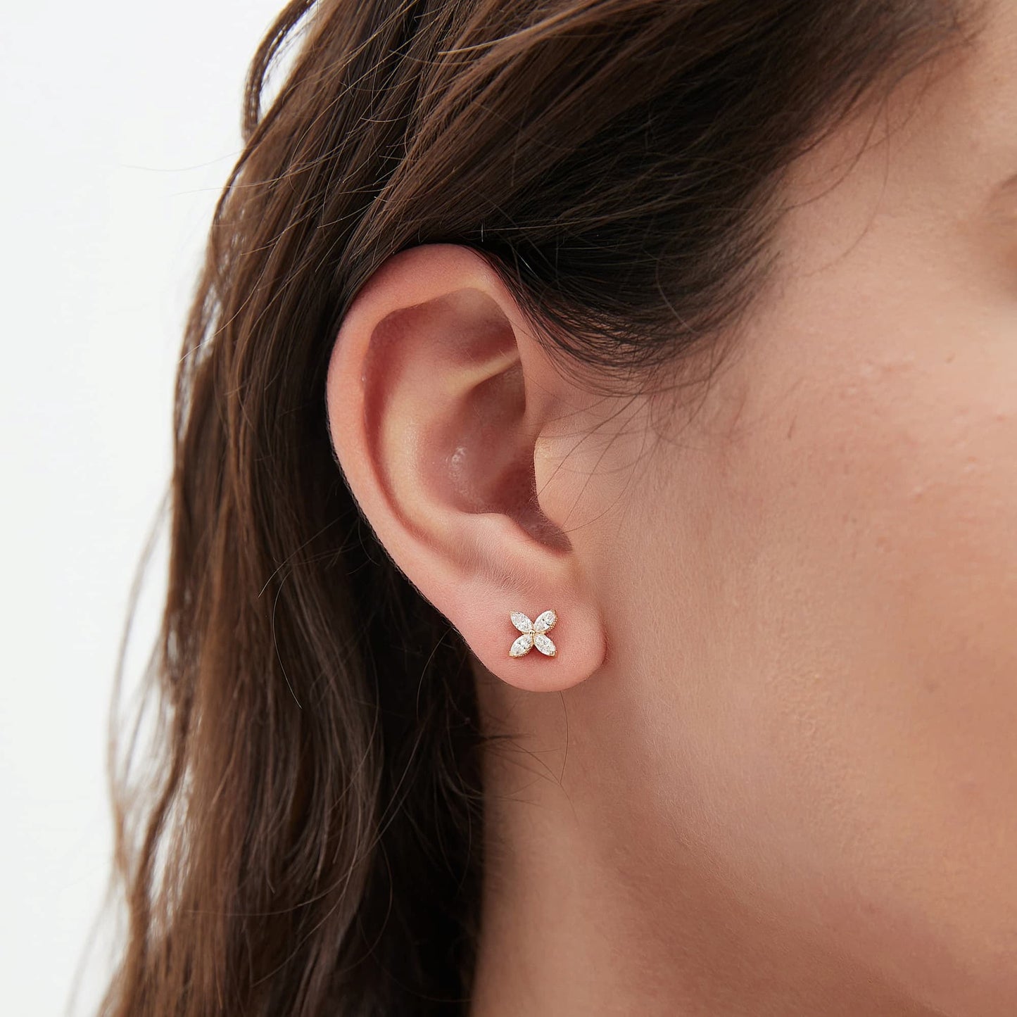 Macro close-up of four-leaf clover diamond stud earrings highlighting the white diamond sparkle and fine prong setting.