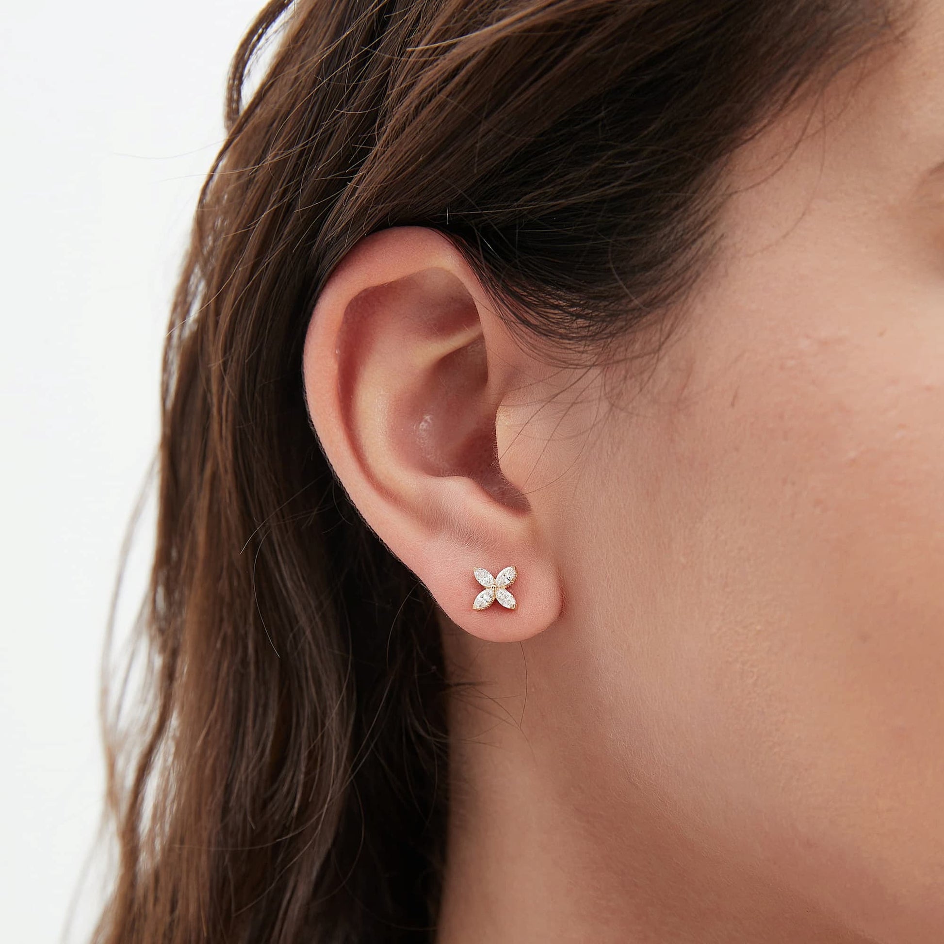 Macro close-up of four-leaf clover diamond stud earrings highlighting the white diamond sparkle and fine prong setting.