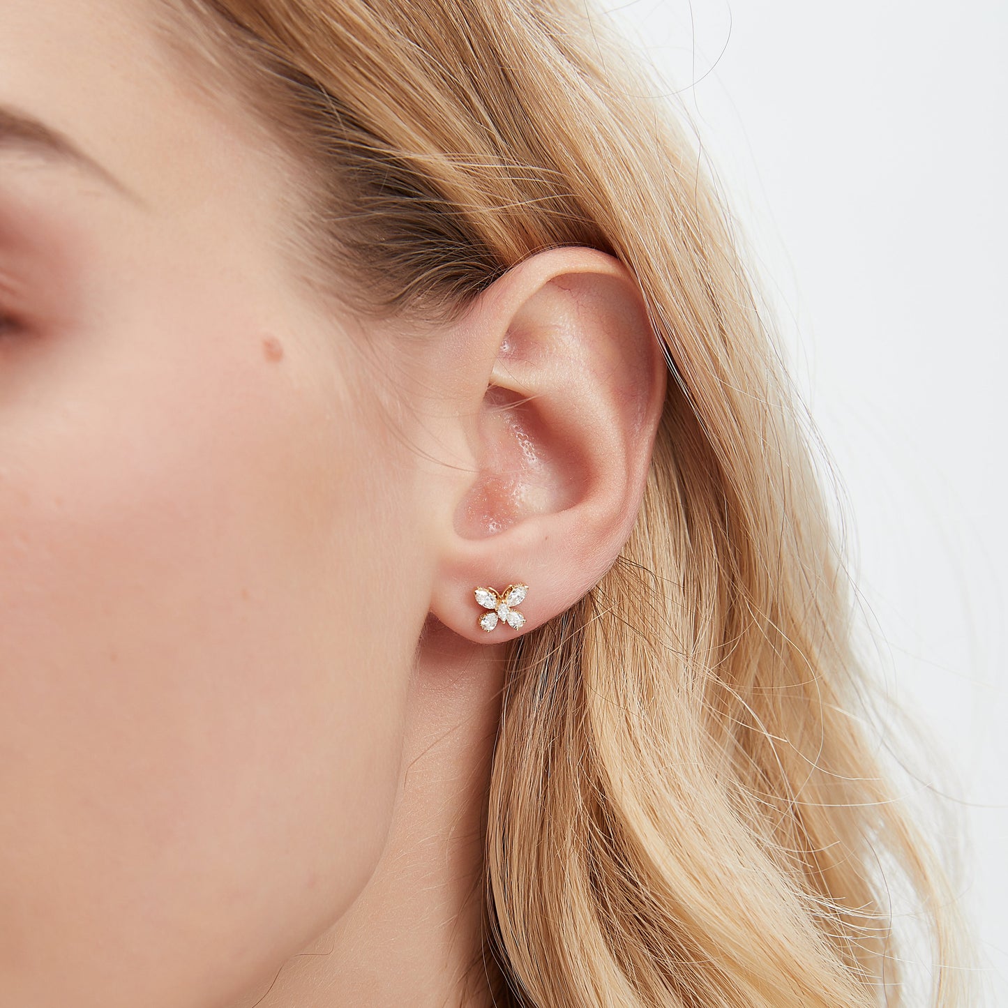 Close-up of a person wearing a floral earring with a plain background