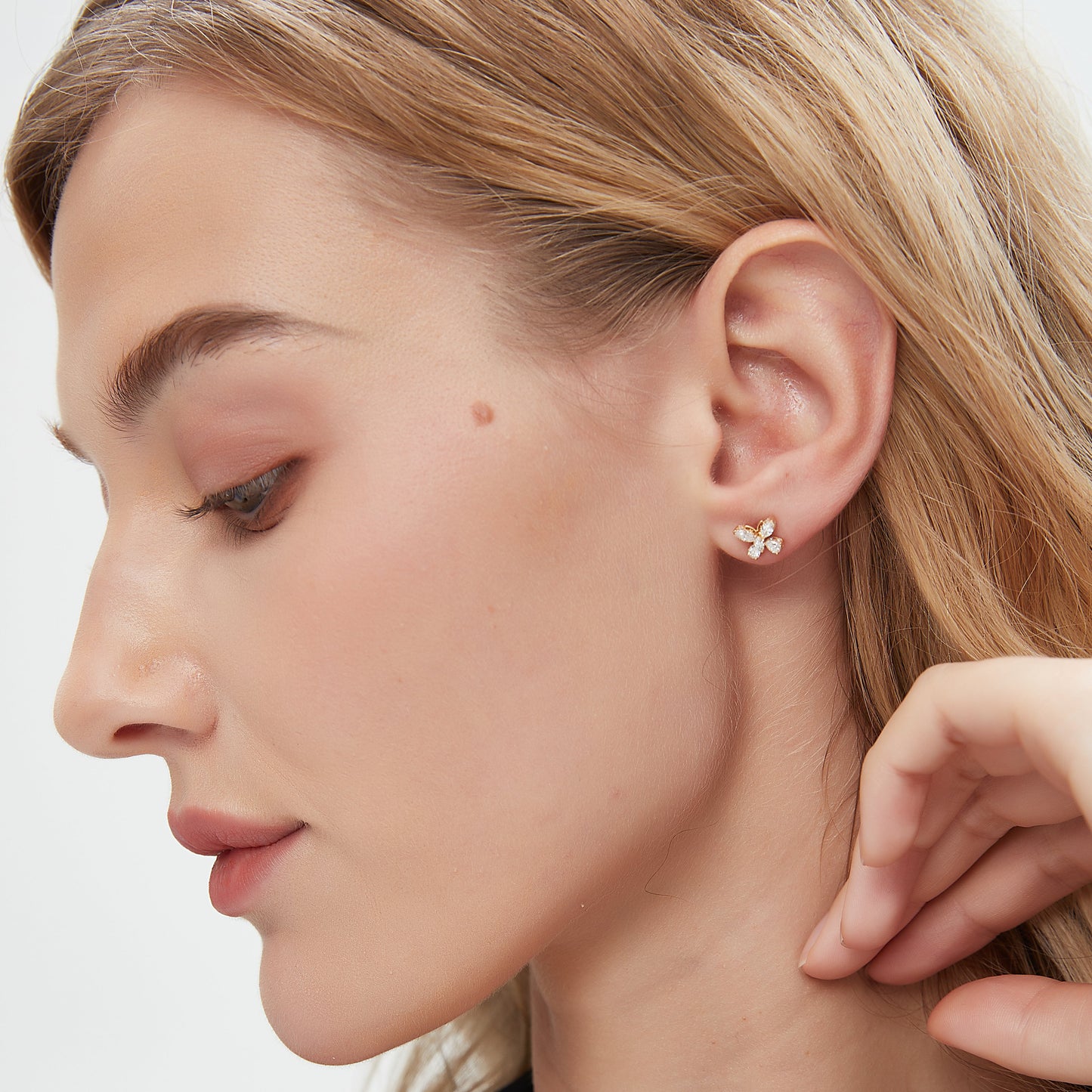 Close-up of a person wearing a small earring on a neutral background