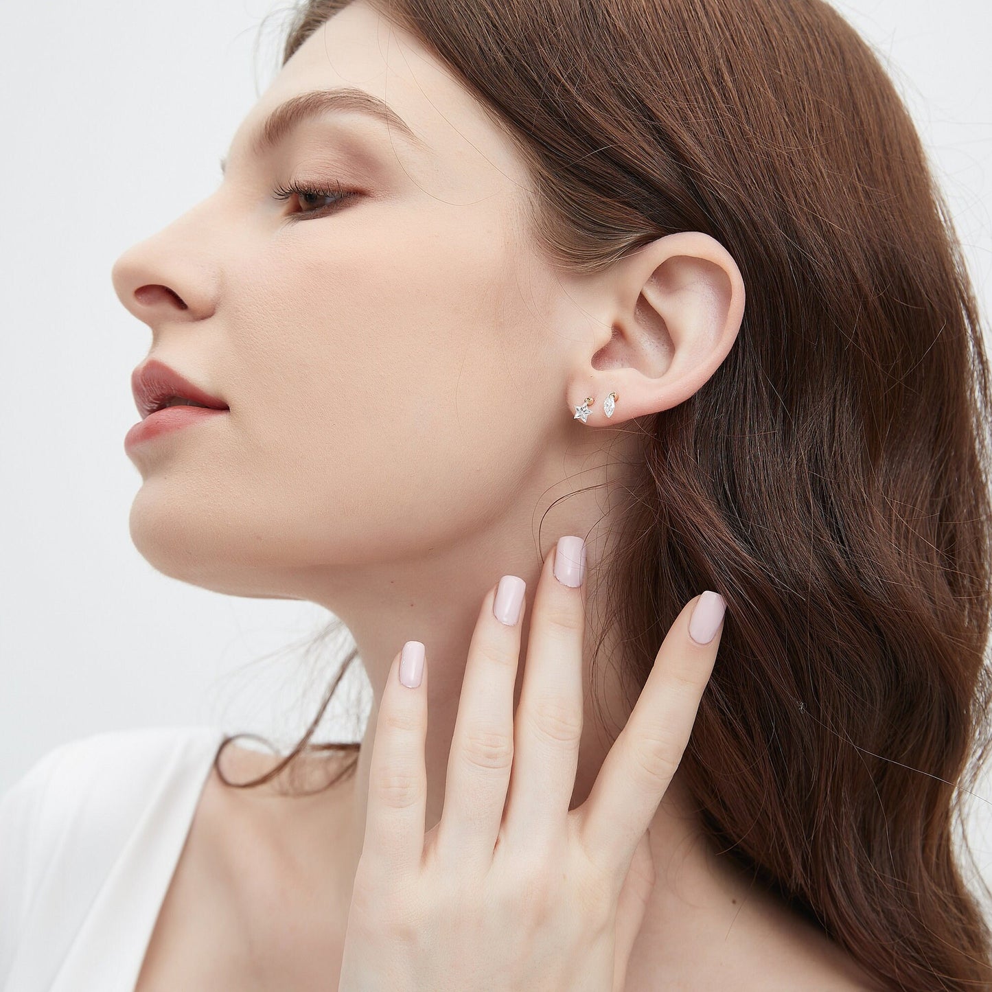 Close-up of a woman wearing silver earrings with a plain background