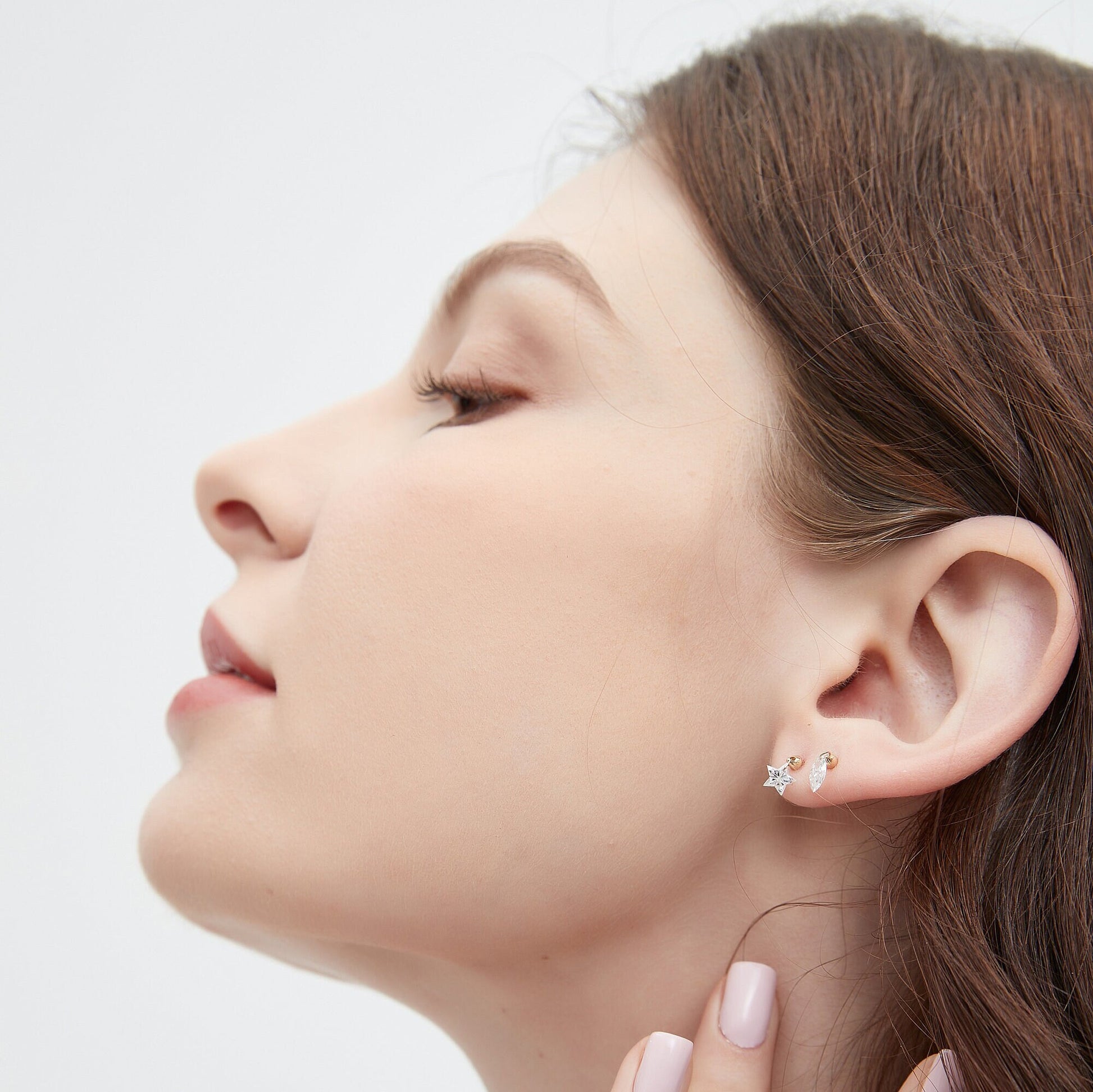 Close-up of a woman wearing earrings with a plain background