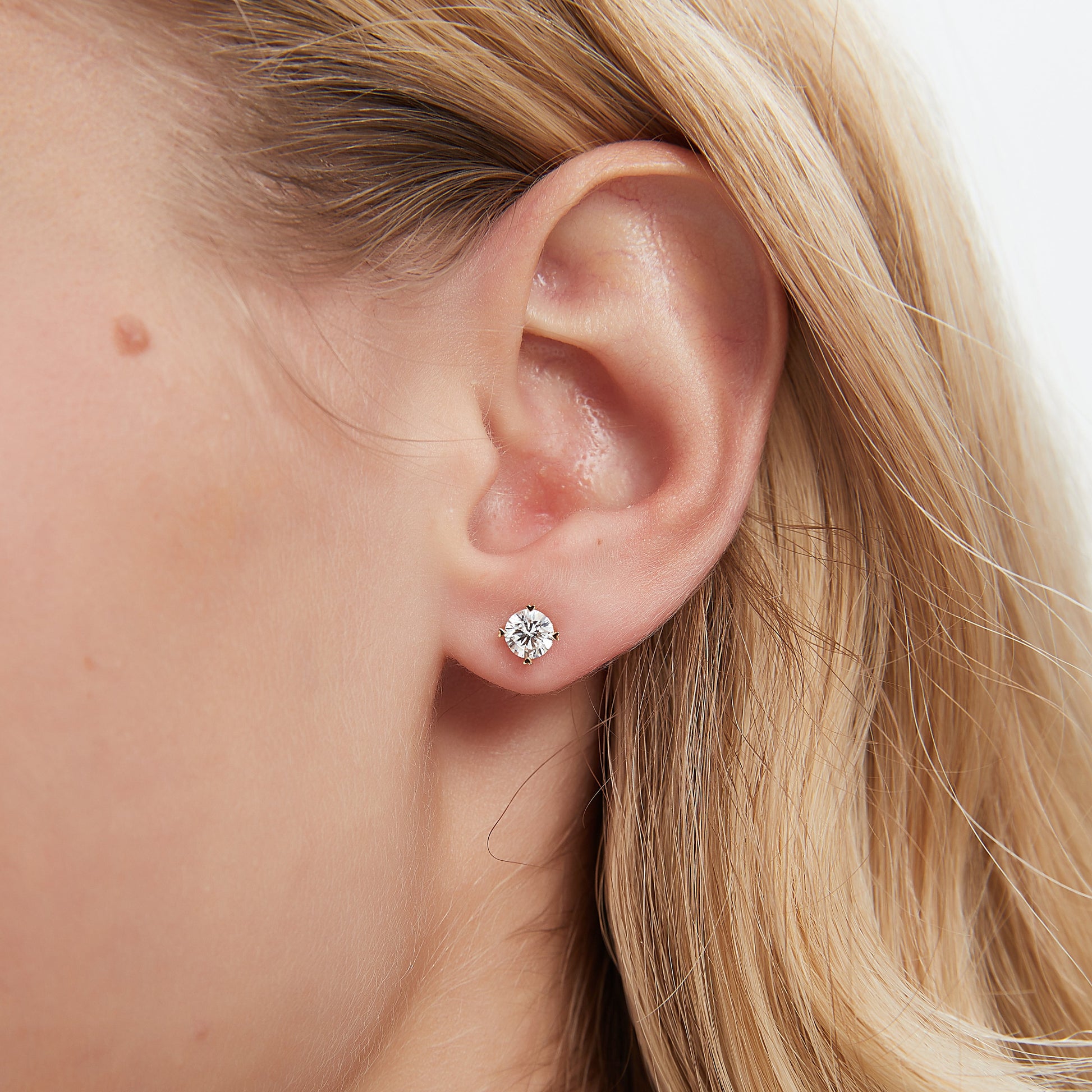 Close-up of a person's ear with a diamond stud earring.