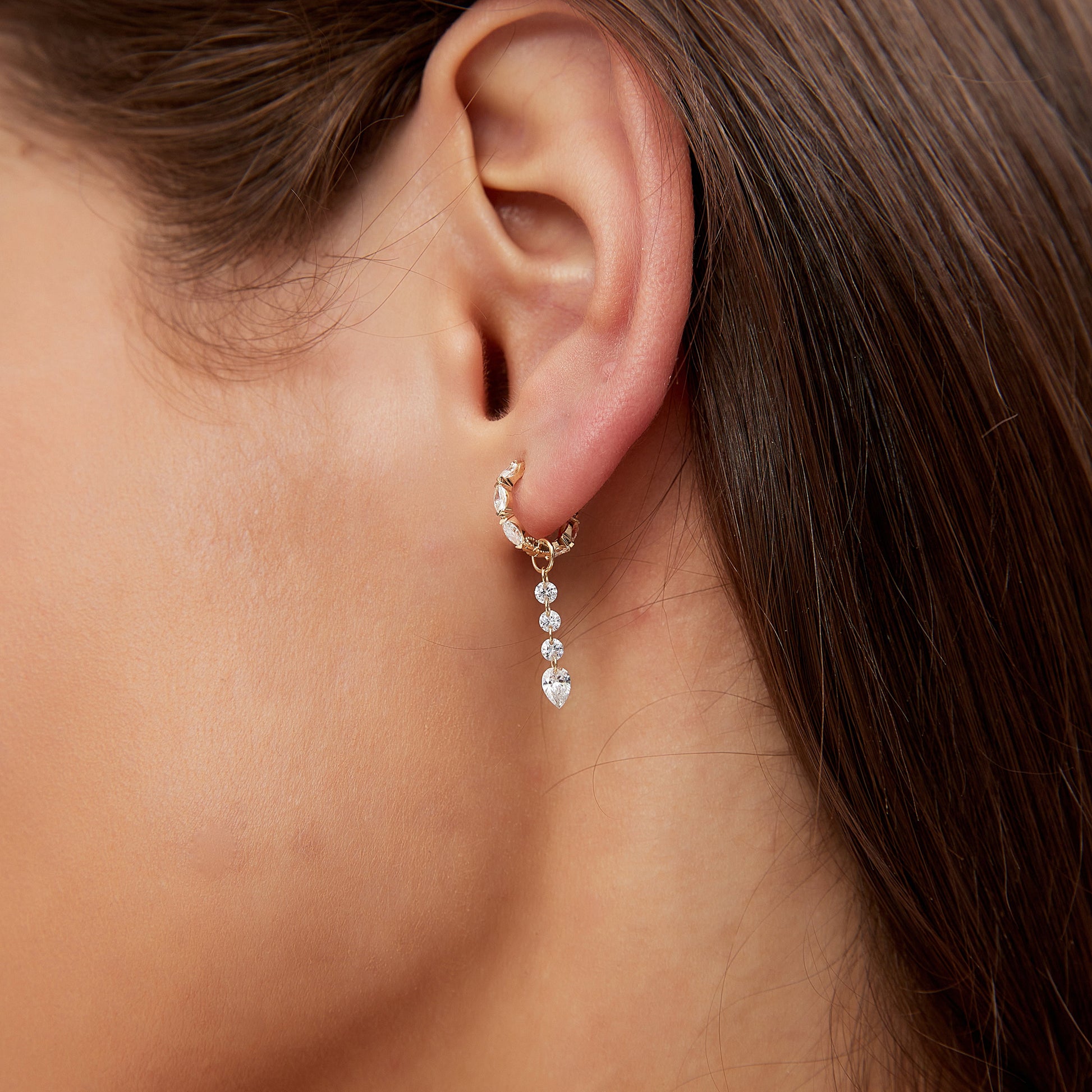 Close-up of an ear wearing a delicate earring with small beads.