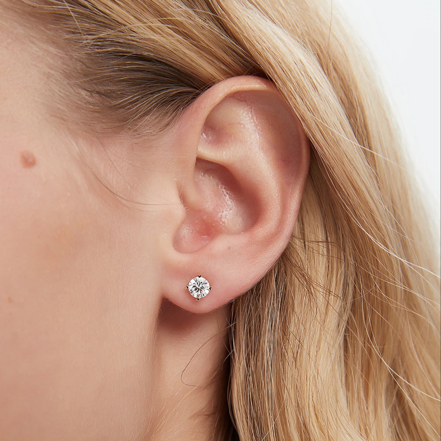 Heart-prong round diamond threaded stud earring in 18K gold worn on ear