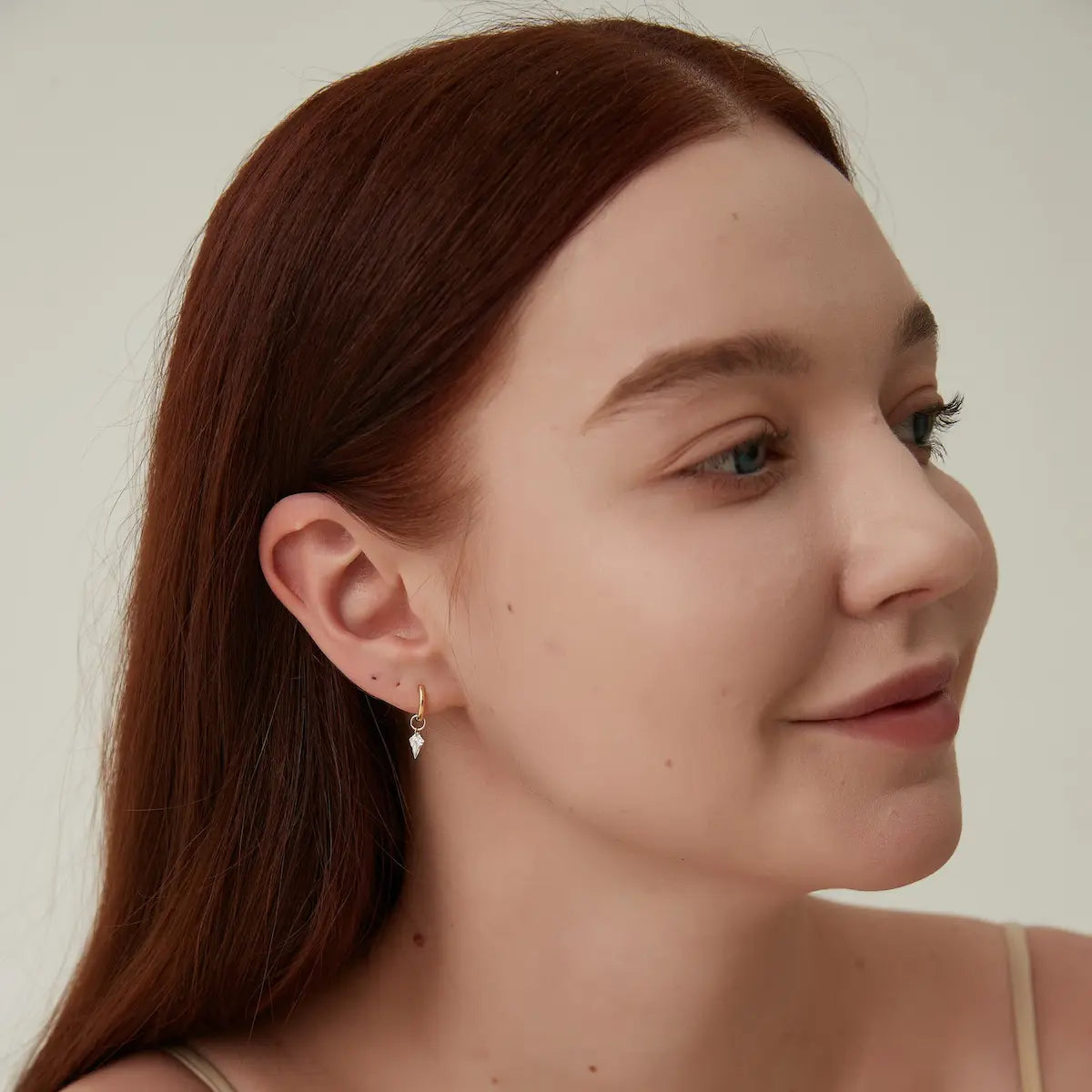This editorial-style model shot features a sophisticated woman wearing the LTM & CO. Kite Diamond Earring Charm, beautifully contextualizing the Architectural Rhythm collection within a modern, refined fashion aesthetic. The model, bathed in soft, natural lighting, faces slightly away from the camera, allowing the 18K solid gold and lab-grown diamond earring charm to serve as the structural focal point of the composition. 