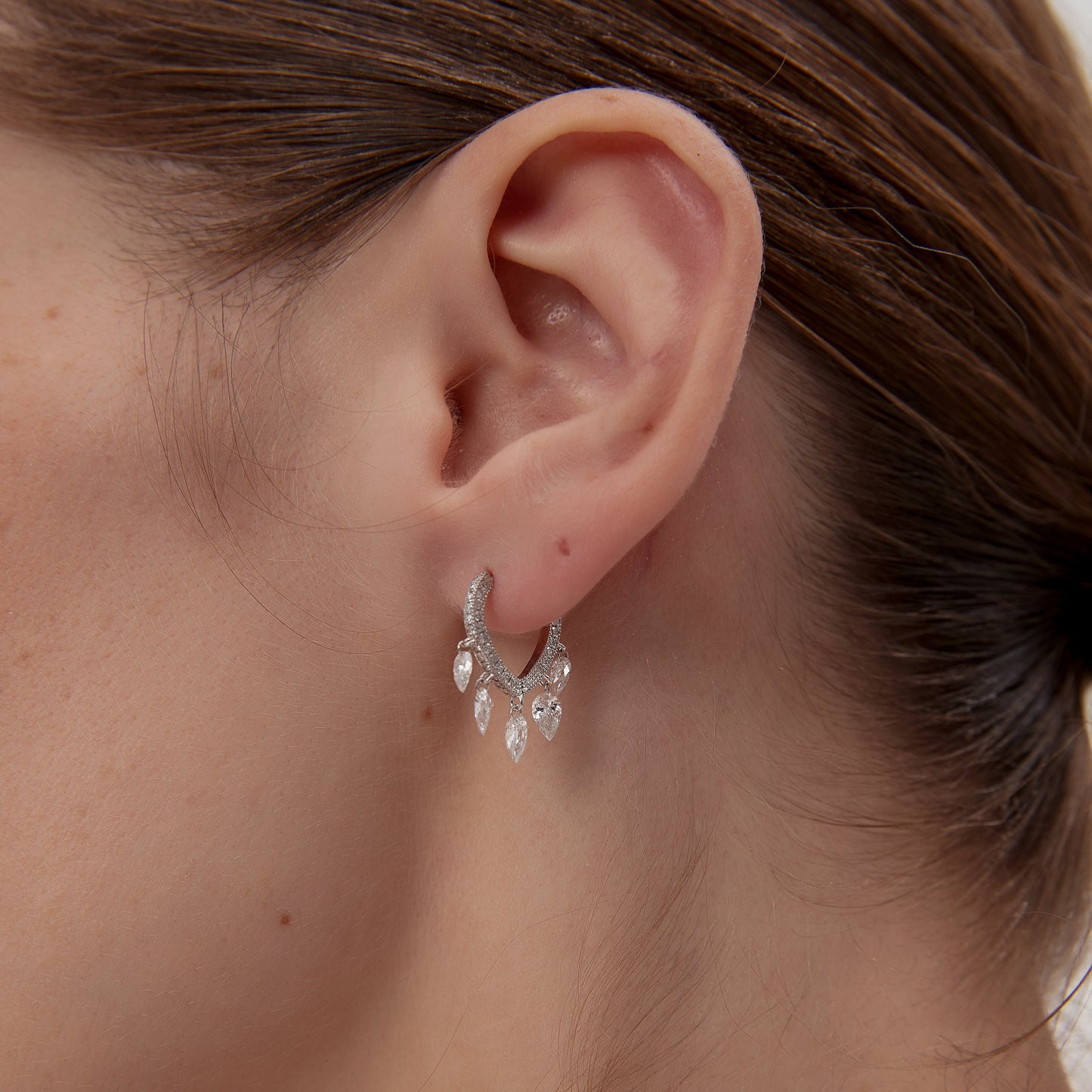 Close-up of an ear wearing a delicate earring with a blurred background
