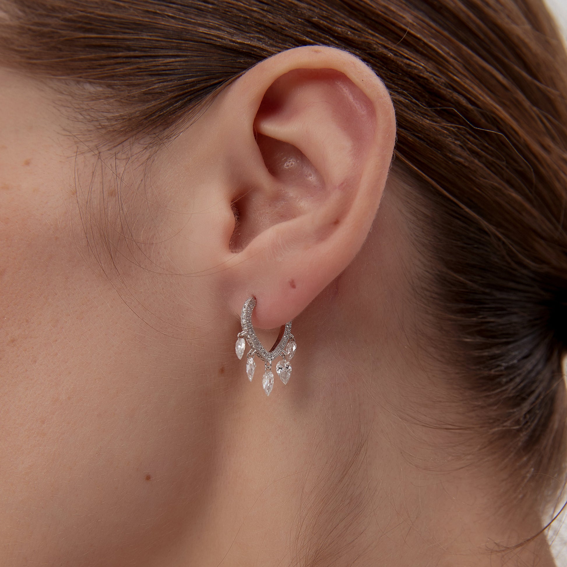 Close-up of an ear wearing a delicate earring with a blurred background