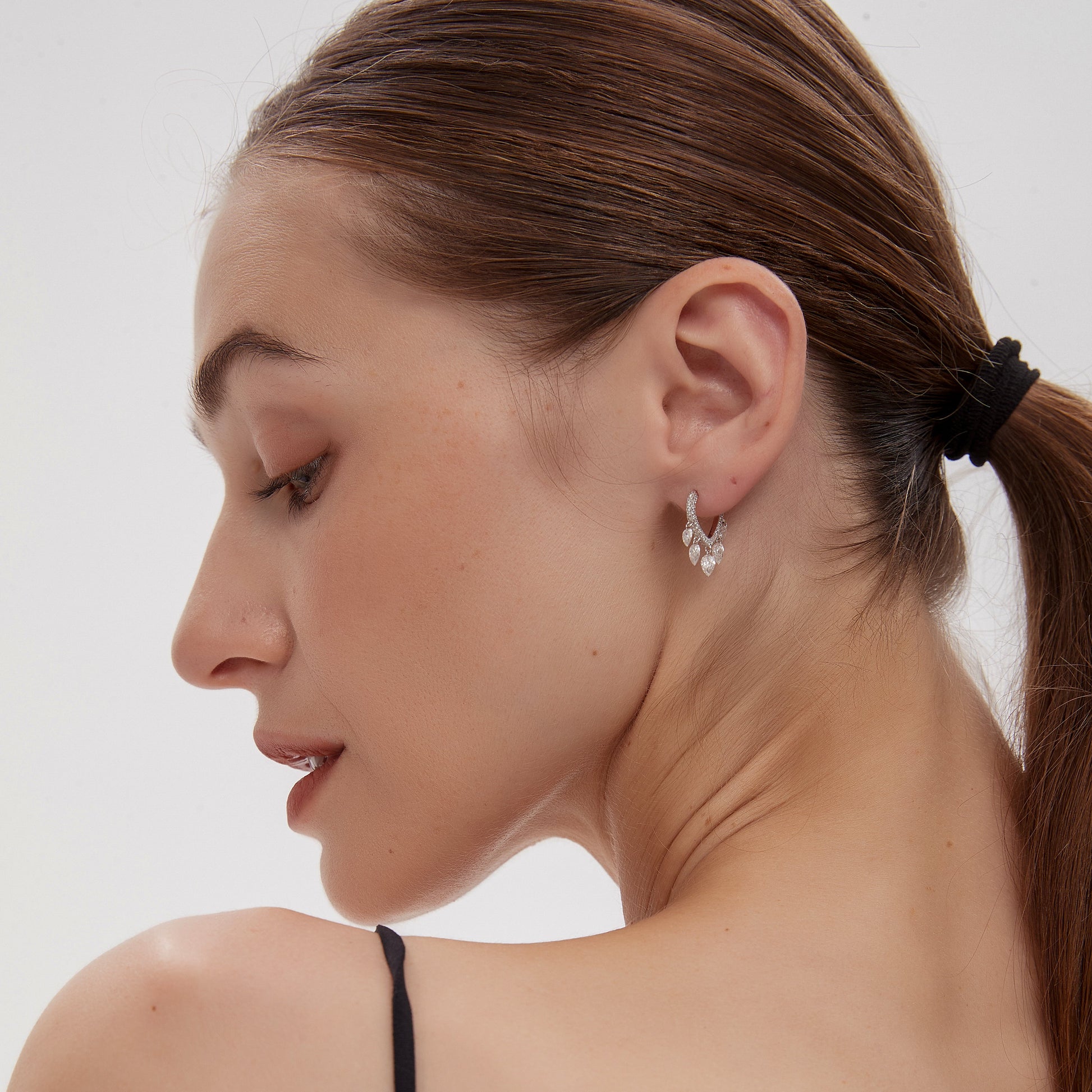 Woman with a ponytail wearing a black top against a white background