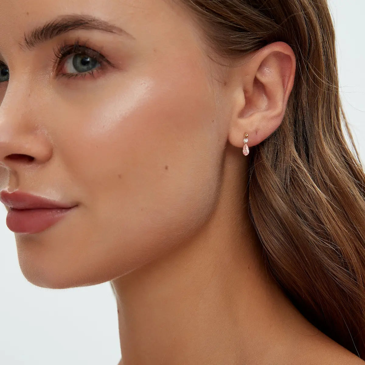 Pink Pear and Round Floating Lab Diamond Stud worn on ear in 18K solid gold, showcasing a pink pear-shaped diamond with a small round white diamond accent