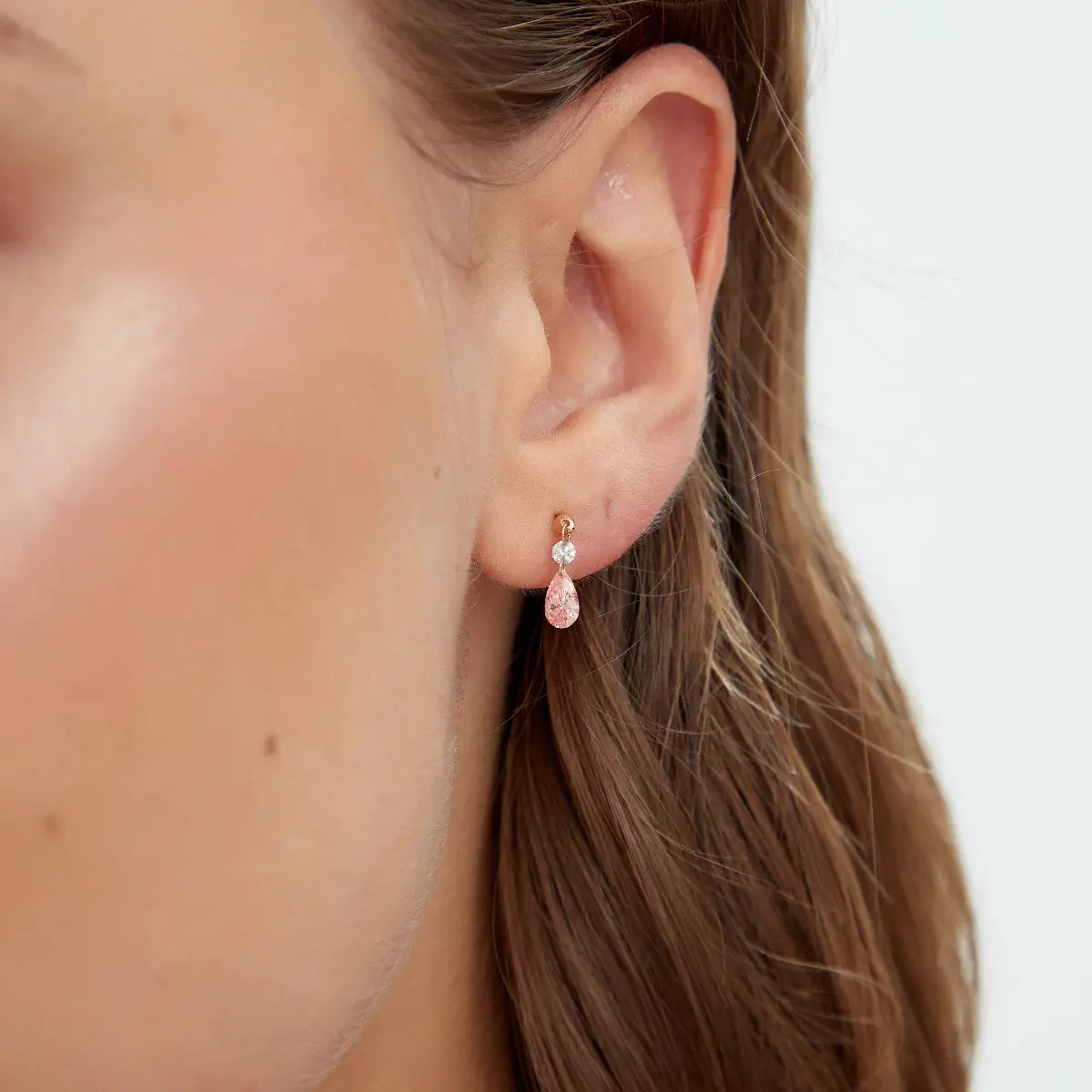 Close-up of Pink Pear and Round Floating Lab Diamond Stud in 18K gold, highlighting the pink pear-shaped diamond and small round white diamond accent