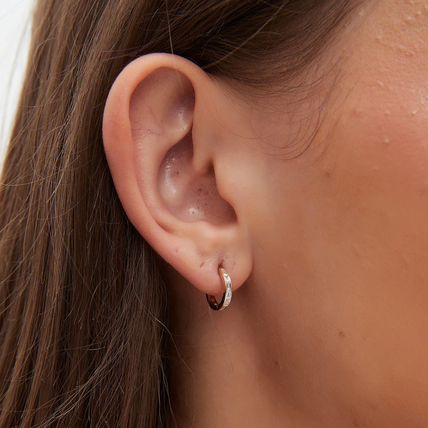 Close-up of VVS straight baguette diamonds in an 8mm 18K gold hoop