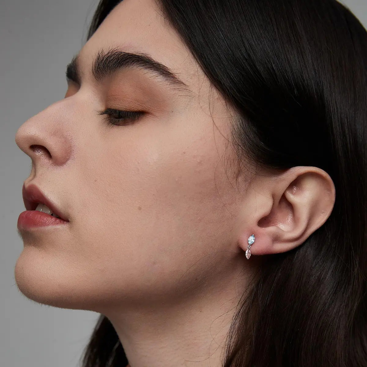 Blue and Pink Marquise Dangle Stud worn on the ear featuring a vivid blue marquise diamond and suspended floating pink marquise dangle. The lightweight sculptural silhouette creates elegant movement and contemporary curated ear styling with cinematic chromatic contrast.