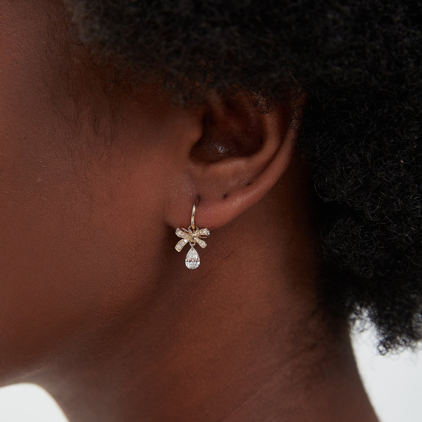 Detail view of butterfly bow design with pear-shaped diamond drop on earring charm