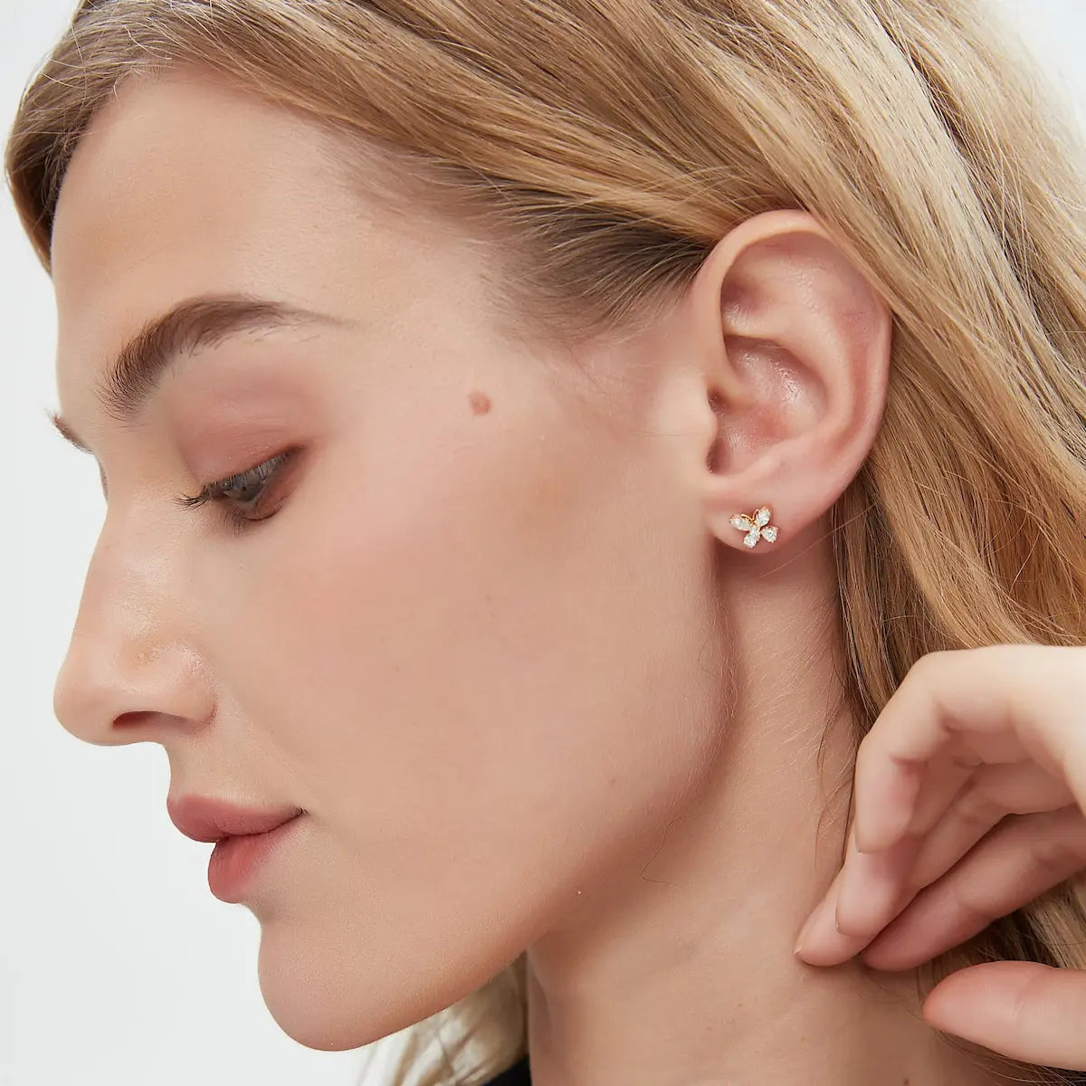 Editorial photo of a model featuring the LTM & CO.™ Whimsical Flight marquise butterfly diamond earring. The soft lighting highlights the sparkle of the white diamonds and the warmth of the 18K solid gold. Embodies the brand's vision of sophisticated, playful, and sustainable luxury jewelry.