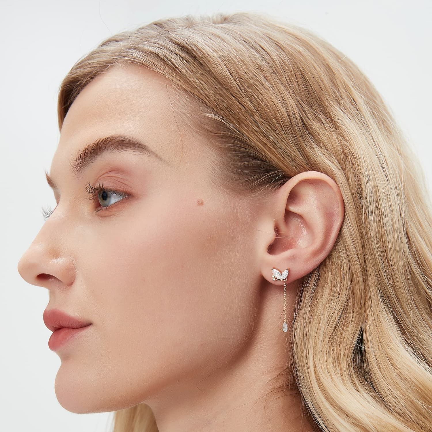 A professional lifestyle photo of the butterfly dangle stud styled on an ear. Demonstrates the kinetic movement and cinematic radiance of the pear-shaped drop, reflecting the Ethereal Flutter collection's poetic design.