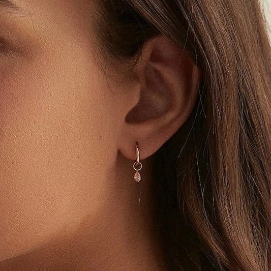A technical side profile view of the Pear Pink Diamond Earring Charm. This image highlights the structural integrity of the 18K solid gold AU750 jump ring and the secure laser-drilled connection of the pear diamond. The side perspective showcases the slim and weightless profile of the drill-set mounting, ensuring the charm hangs perfectly and moves fluidly with the wearer. The consistent high-polish finish and the alignment of the fancy light pink diamond are clearly visible, emphasizing quality.