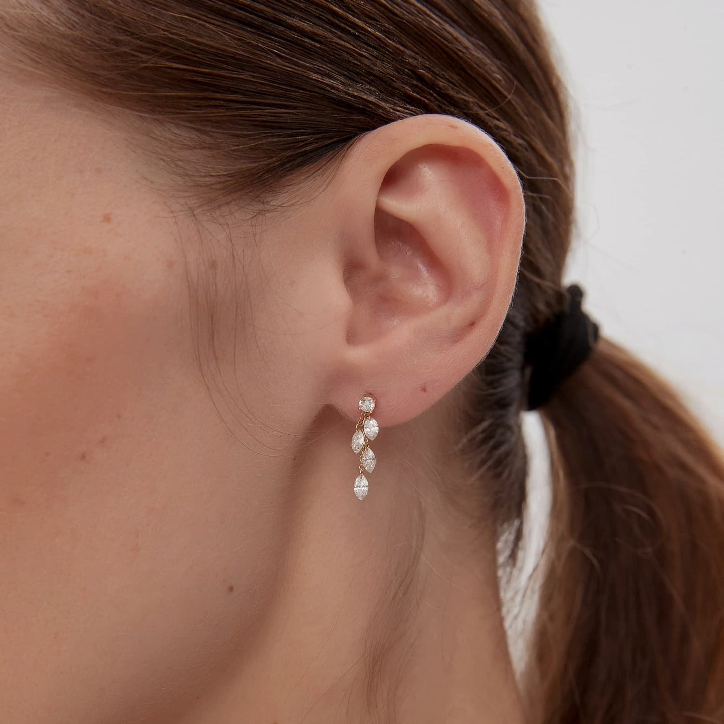 A detailed macro close-up focusing on the master craftsmanship of the Round & Marquise Dangle Stud. The photograph reveals the precise settings of the anchoring round diamond and the four cascading marquise stones, showcasing their exceptional VVS-VS clarity. The high-definition image emphasizes the structural beauty of the fine-link 18K gold chain and the architectural precision of LTM Jewels. This view is essential for appreciating the crystalline fire of the 0.50ctw diamonds and the technical quality.
