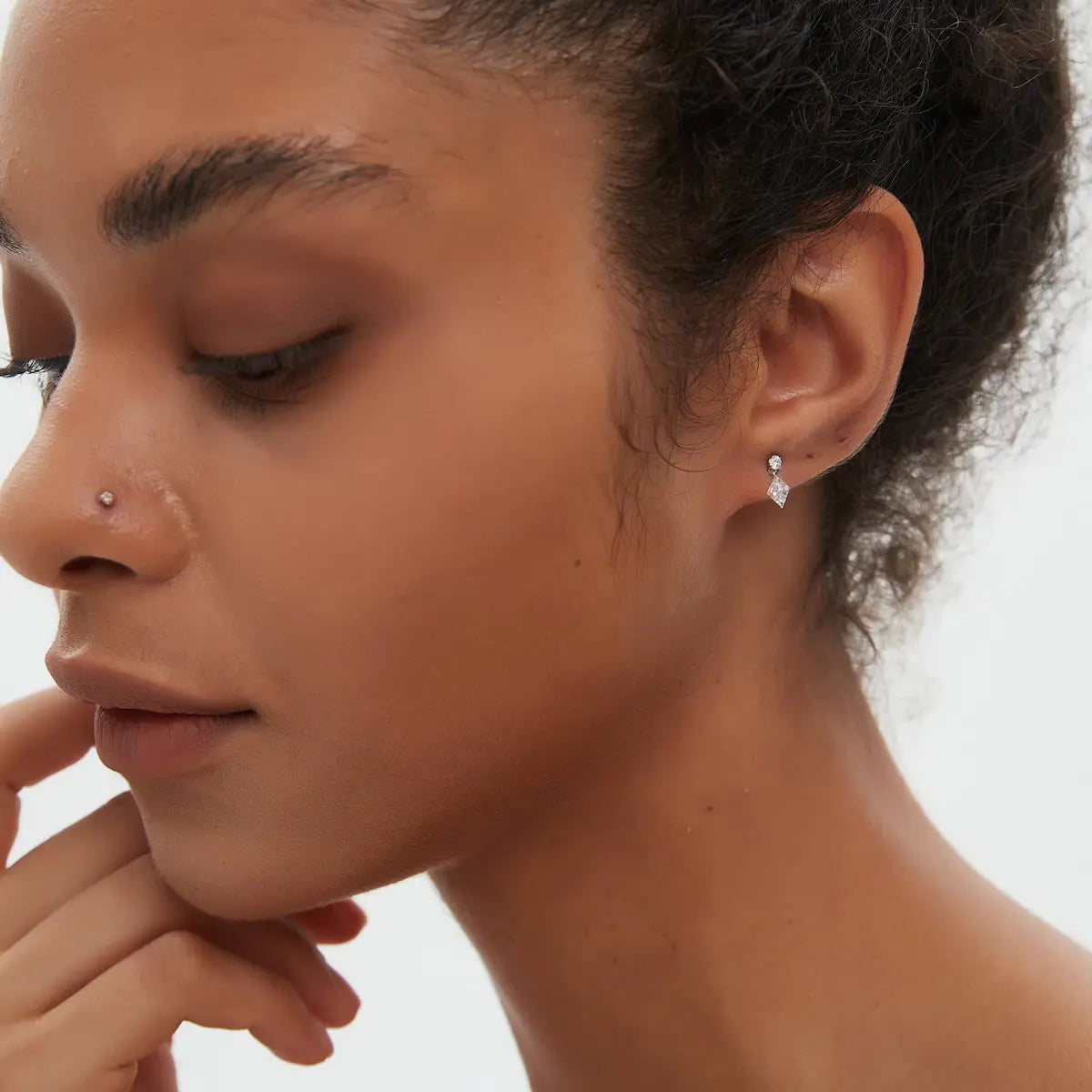 Model wearing the Lozenge Dangle Threaded Stud from the Architectural Rhythm collection. The floating geometric diamonds and sculptural gold silhouette create cinematic brilliance, fluid movement, and modern editorial luxury jewelry styling.
