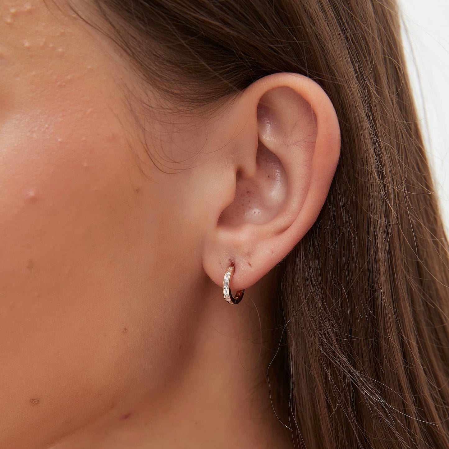 On-ear styling of a luxury minimalist ear stack featuring baguette hoops
