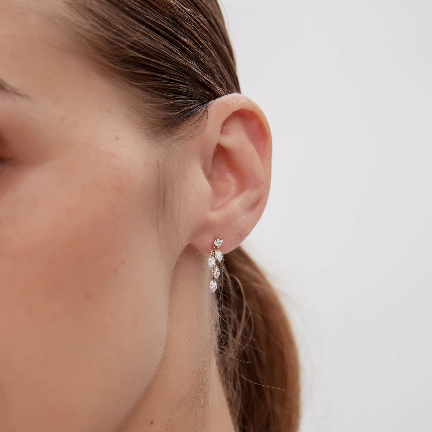 A technical side profile view of the Round & Marquise Dangle Stud. This image highlights the structural integrity of the 18K solid gold AU750 construction and the professional threaded screw back engineered for a secure 24/7 permanent-wear fit. The side perspective showcases the depth of the anchoring diamond setting and the fluid drape of the cascading chain with its four marquise diamonds. The consistent high-polish finish and the alignment of the 0.50ctw diamonds are clearly visible.