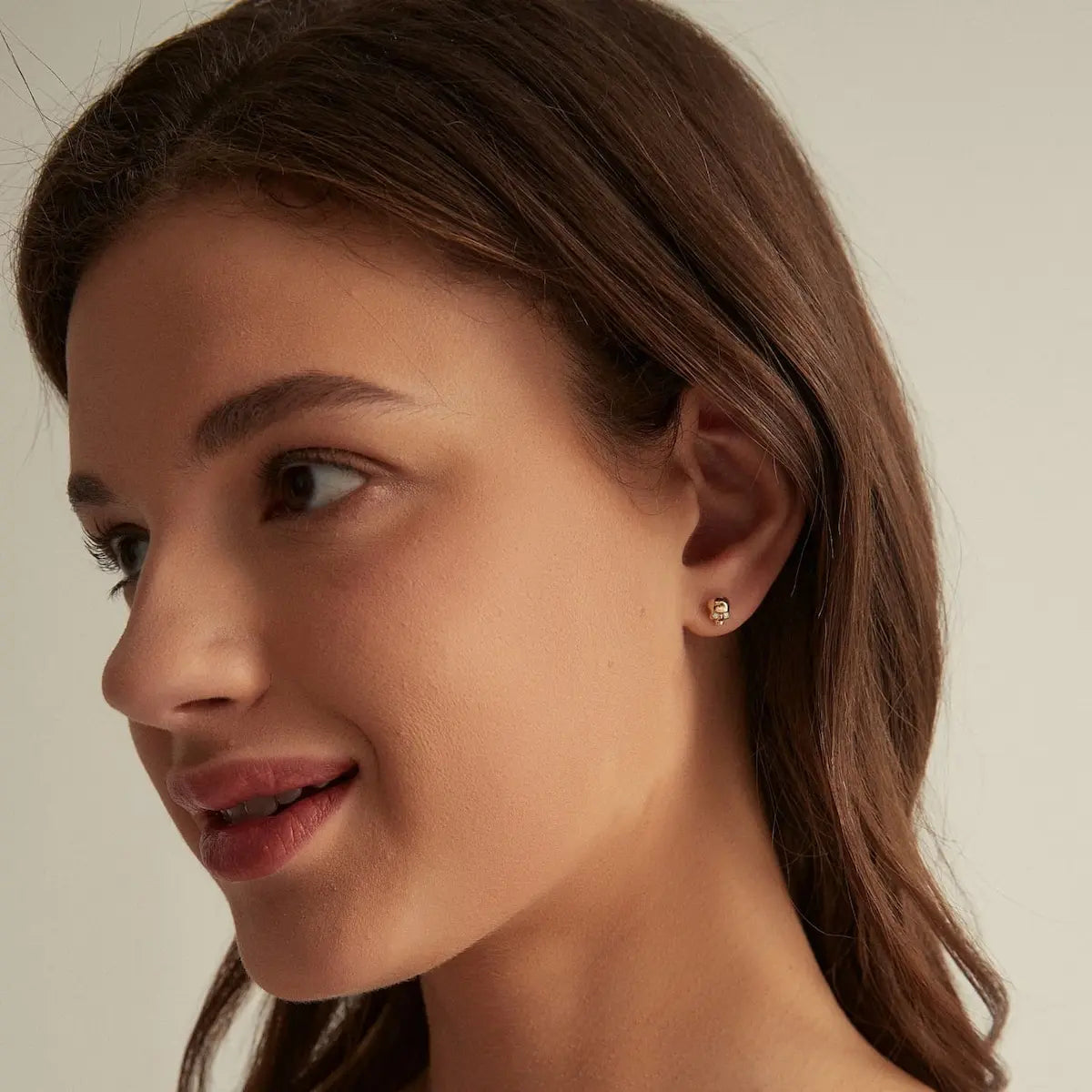 A fashion editorial photograph featuring the Diamond Skull Threaded Stud by LTM Jewels. The model is seen wearing the stud, highlighting its role as a cinematic heirloom and a bold statement piece. The contrast between the rebellious skull motif and the luxury of 18K gold and natural diamond is prominent. This image captures the Memento Mori design philosophy, illustrating how the piece adds an atmospheric and sophisticated edge to a high-end fashion look and luxury jewelry collection.
