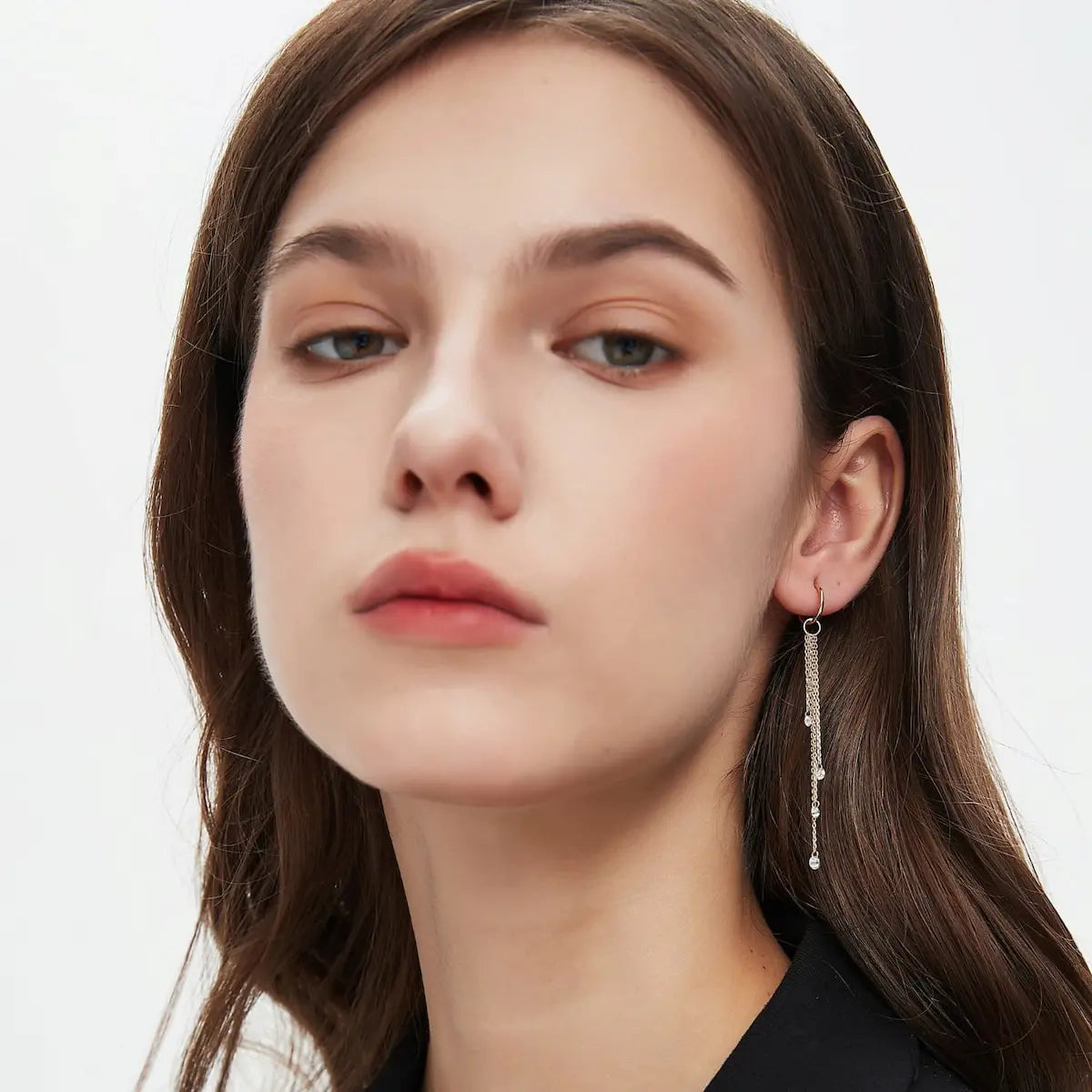 A professional lifestyle image showing the Marquise Linear Waterfall Charm styled on an ear. Attached to an 18K gold hoop, the charm demonstrates fluid motion and the dramatic shimmer of its five marquise diamonds. This perspective highlights the elongated silhouette of the 'Celestial Drift' design and how it captures light from every angle, making it an essential piece for a modern curated ear stack. The natural lighting emphasizes the fire and brilliance of the D-E color diamonds.