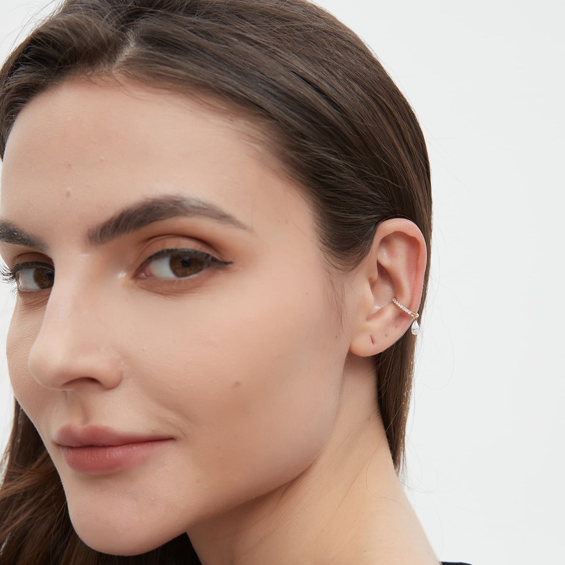 Model wearing a minimalist pear diamond dangle ear cuff on the cartilage