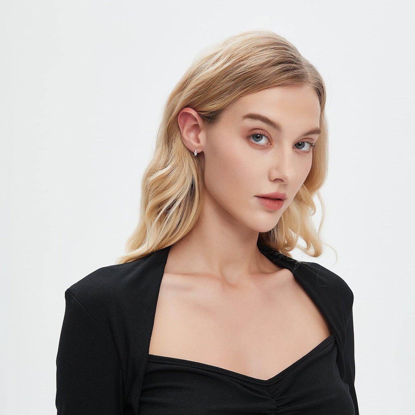 A professional lifestyle photograph showing the Pear Pavé Hoop styled on a model's ear. The 8mm 18K solid gold hoop is shown in a curated ear stack, illustrating how the pear centerpiece and pavé-set diamonds capture light with a cinematic radiance. This perspective highlights the architectural silhouette and the seamless fit of the hinge closure. Captured in natural lighting to emphasize the fire of the D-E color diamonds, perfect for modern luxury jewelry styling inspiration.