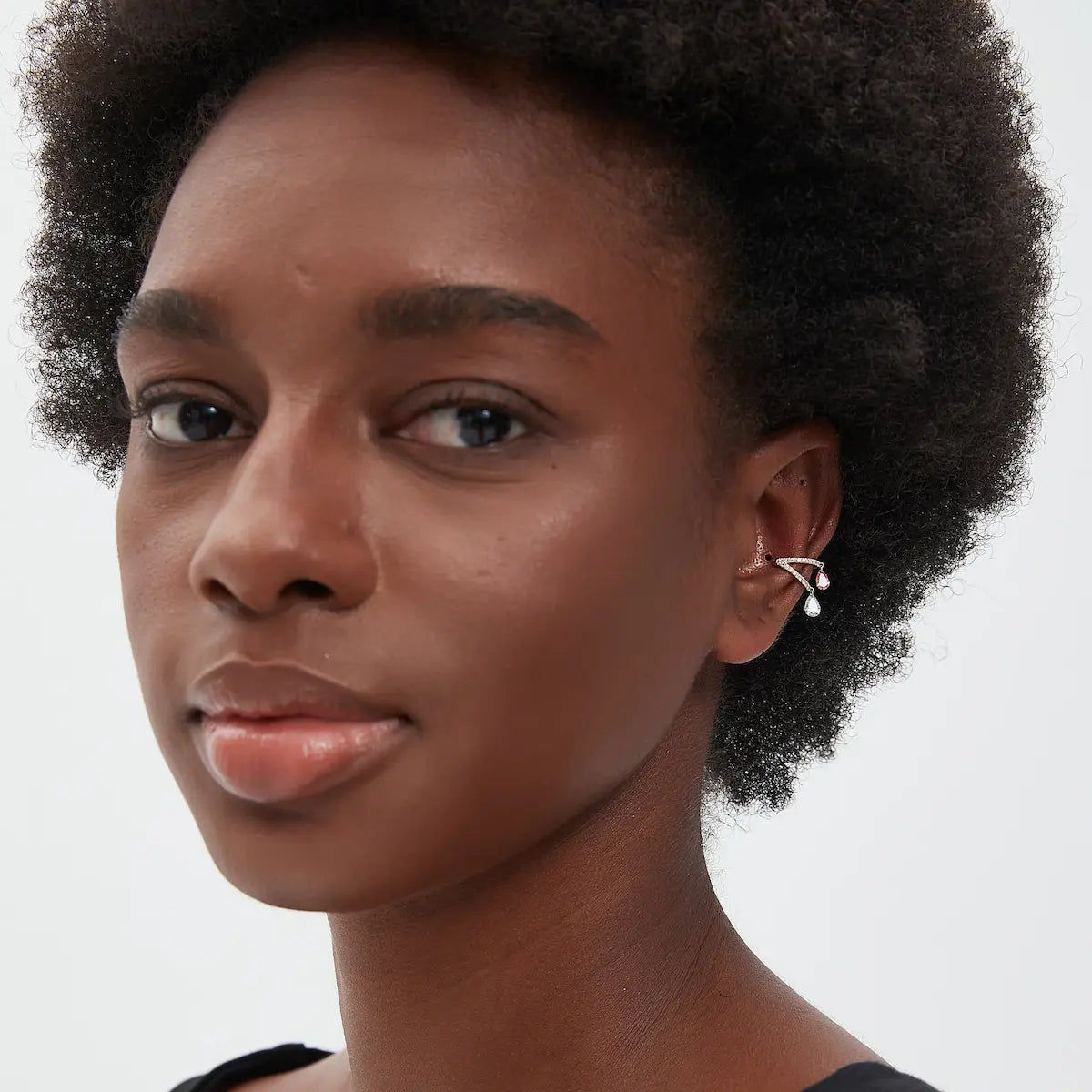 A fashion editorial photograph featuring the Pink White Pear Pavé Dangle Ear Cuff by LTM Jewels. The model is seen wearing the cuff, illustrating its role as a cinematic heirloom and a bold statement of non-pierced luxury. The contrast between the radiant diamonds and the luxurious 18K gold is prominent, showcasing the 'Liberated Elegance' design philosophy. This image captures the atmospheric grace of the piece, showing how it adds a structural glow to a high-fashion look and luxury jewelry collection.