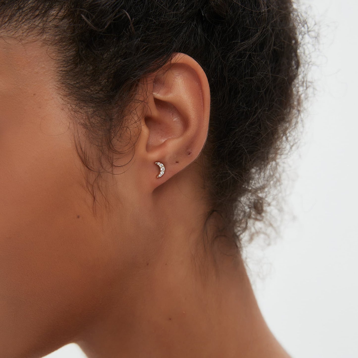 Close-up of natural diamond set in moon-shaped threaded stud earring