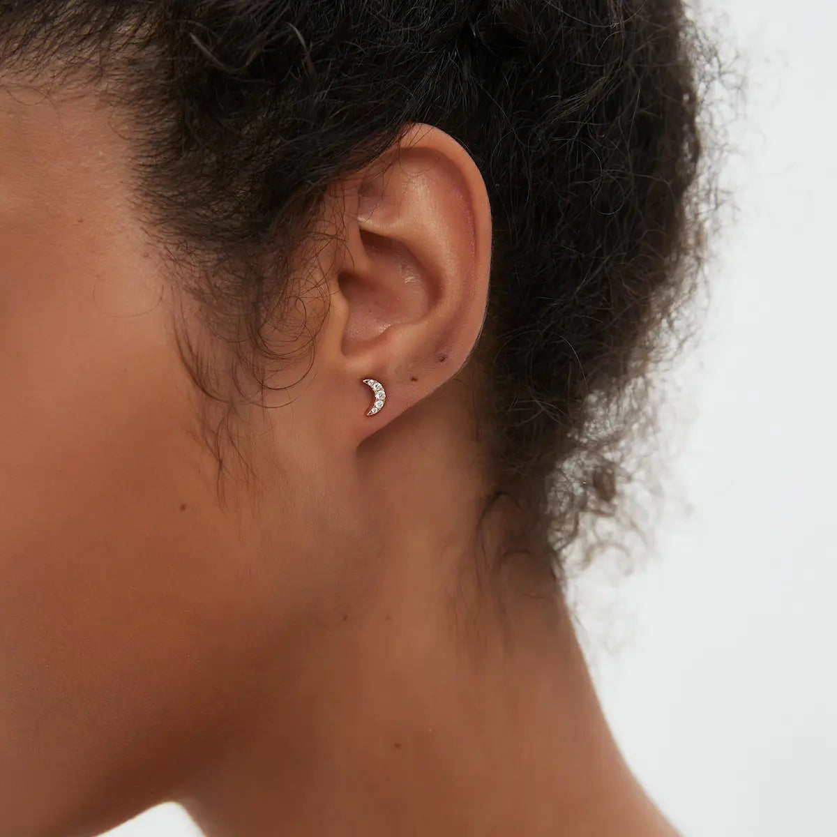 Macro close-up of the Diamond Crescent Moon Stud handcrafted in solid 18K gold. The precision-set natural white diamonds and sculptural crescent silhouette create subtle lunar brilliance, refined architectural craftsmanship, and contemporary minimalist fine jewelry styling.
