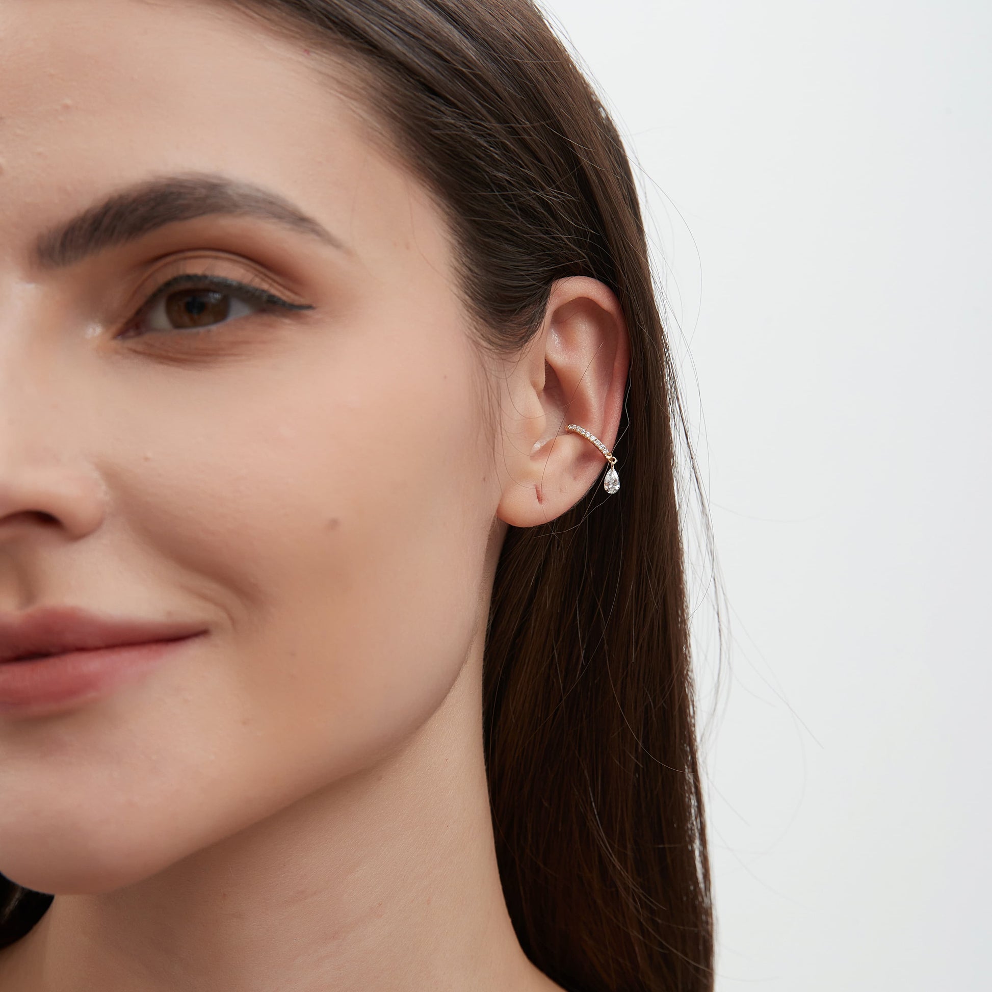 Lifestyle styling of a minimalist ear stack featuring a pear diamond dangle cuff