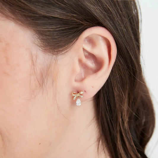 High-definition close-up showcasing the intricate 18K gold butterfly bow and the premium pear-cut lab diamond drop, highlighting the exceptional VVS-VS clarity and D-E color of the floating gemstone.