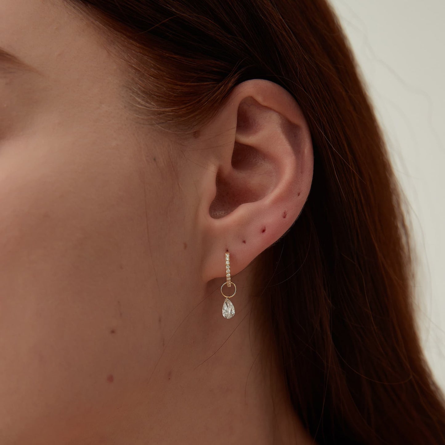 Detail of the laser-drilled single pear white diamond in 18K gold.