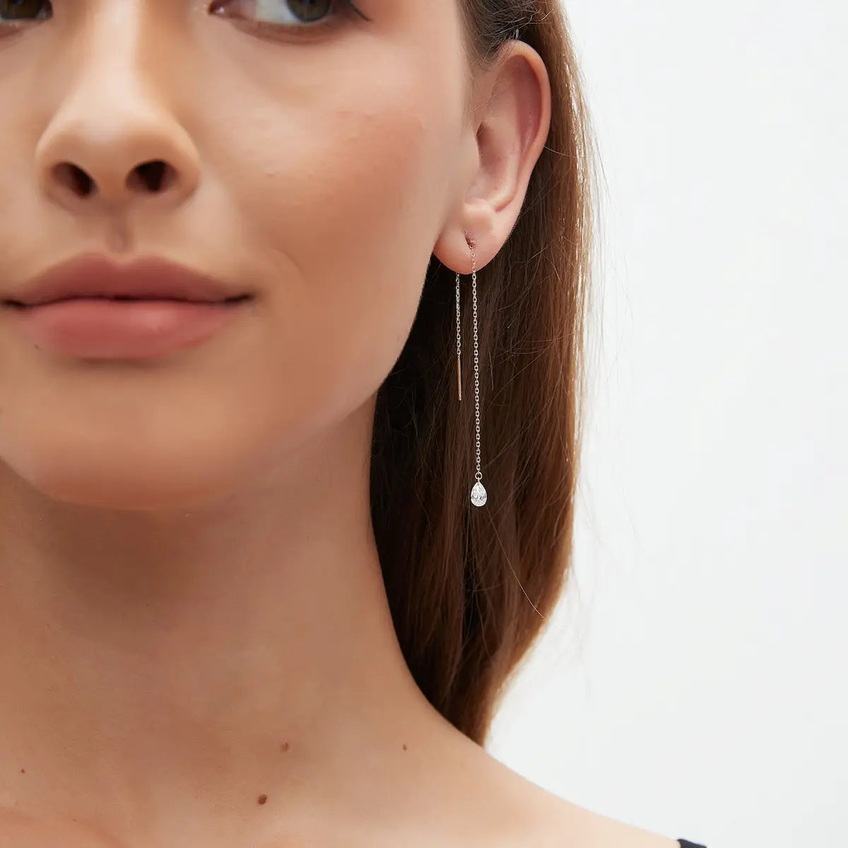 Lifestyle photography of a model wearing the LTM Jewels pear diamond threader earring, showcasing its weightless elegance and sophisticated sweep against the neckline. The aesthetic emphasizes a "celestial drift" theme, highlighting the piece as a contemporary heirloom. This shot demonstrates the earring's scale and its ability to transition from a minimalist office accessory to a high-fashion statement for evening events, all while being hypoallergenic and shower-safe.