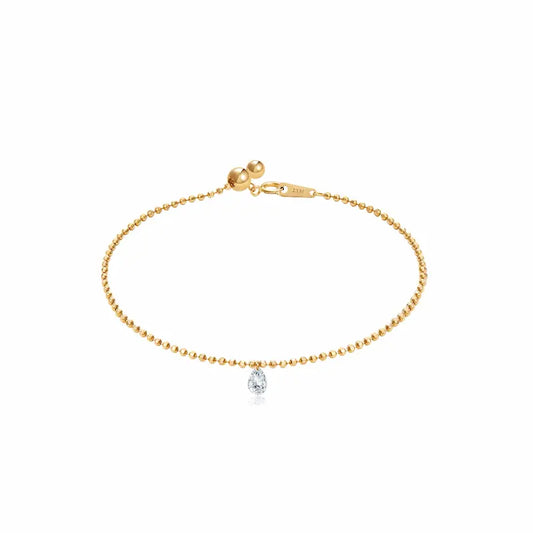 A high-resolution photo of the Pear Drilled Diamond Bracelet by LTM & CO.™. Features a 0.2ct laser-drilled pear diamond floating on an 18K solid gold diamond-cut bead chain. The image highlights the crystalline D-E color and VVS-VS clarity of the gemstone, showcasing the "Pure Brilliance" of the minimal setting which allows the diamond to catch light from every angle for a cinematic glow.